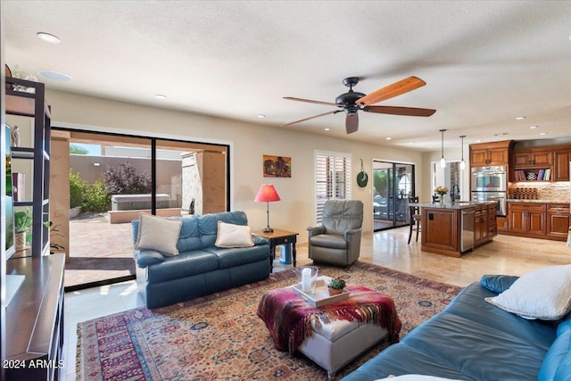 living room featuring ceiling fan, sink, light tile patterned floors, and a textured ceiling