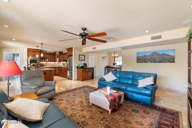 living room featuring ceiling fan with notable chandelier and sink