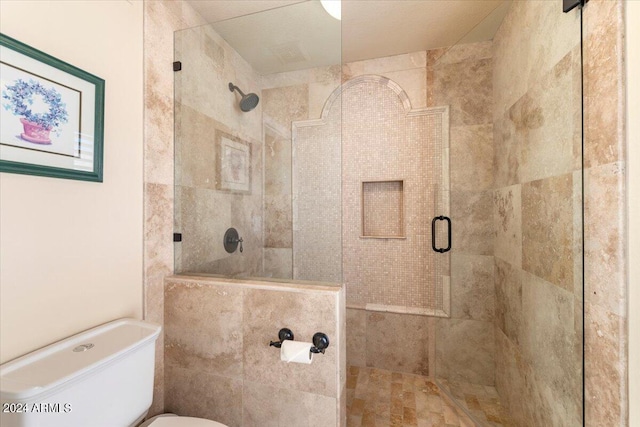 bathroom featuring a shower with door and toilet