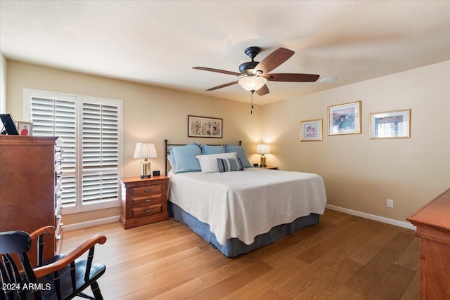 bedroom with ceiling fan, light hardwood / wood-style floors, and multiple windows