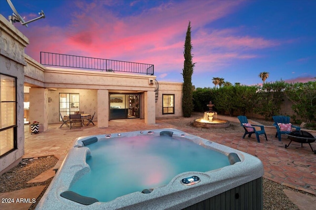 pool at dusk featuring a patio area, a hot tub, and an outdoor fire pit