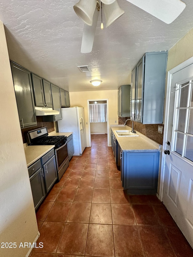3211 W Campbell Ave, Phoenix, AZ 85017 - kitchen featuring stainless steel gas stove, under cabinet range hood, white refrigerator with ice dispenser, light countertops, and dark tile patterned flooring
