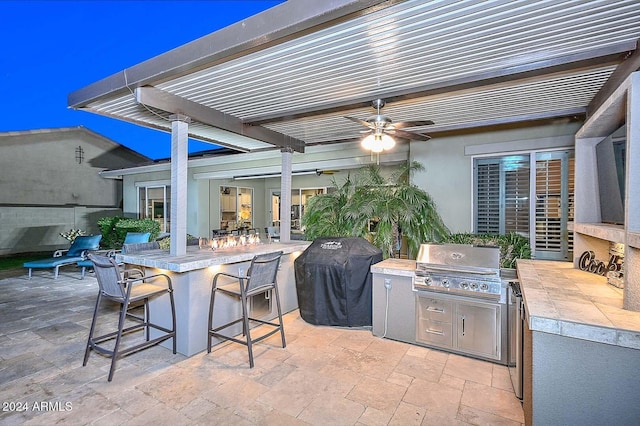 view of patio / terrace featuring ceiling fan, a grill, an outdoor bar, and exterior kitchen