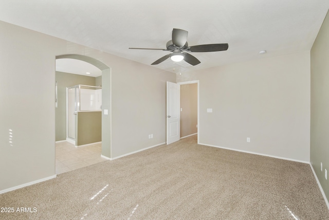 unfurnished room featuring light carpet, baseboards, arched walkways, and ceiling fan