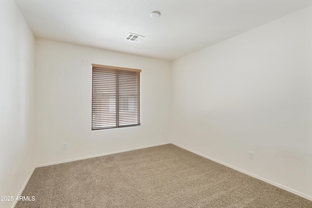 spare room featuring carpet, visible vents, and baseboards