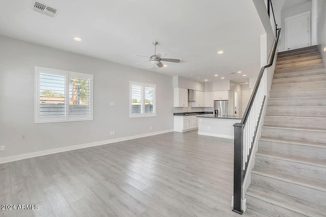 unfurnished living room with ceiling fan and light wood-type flooring