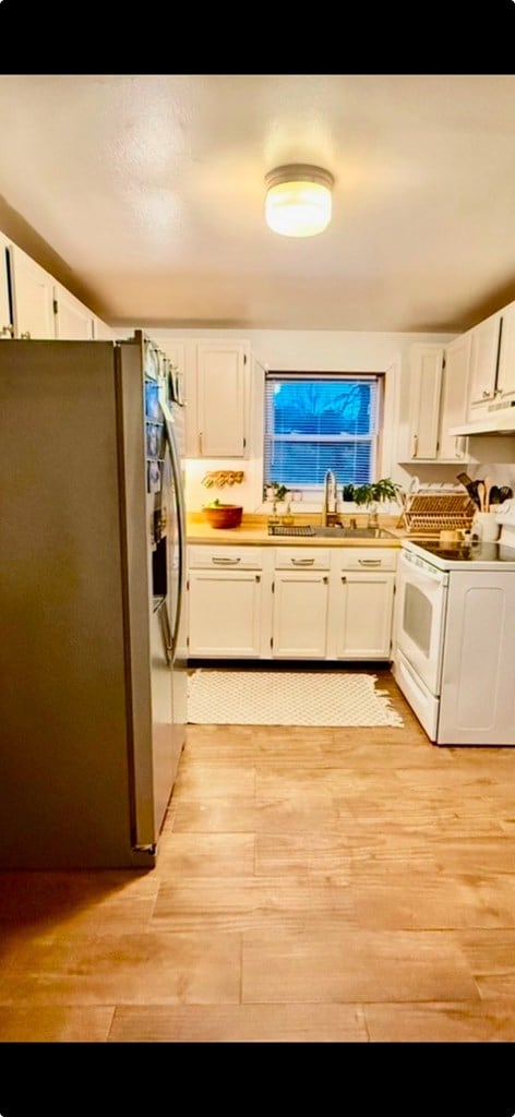 kitchen with white cabinetry, white electric stove, stainless steel refrigerator with ice dispenser, and a sink