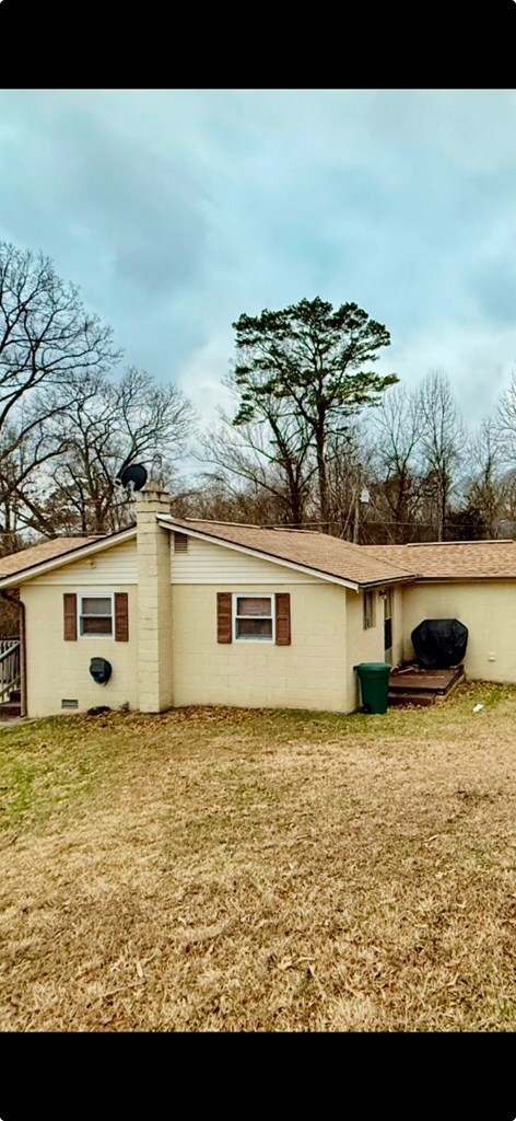 rear view of house with a yard and concrete block siding