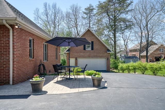 view of property exterior with brick siding, roof with shingles, a patio area, and outdoor dining space