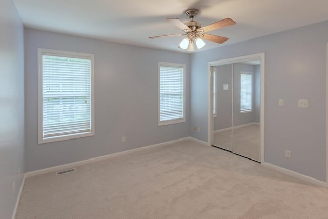 unfurnished bedroom with light carpet, multiple windows, visible vents, and a closet