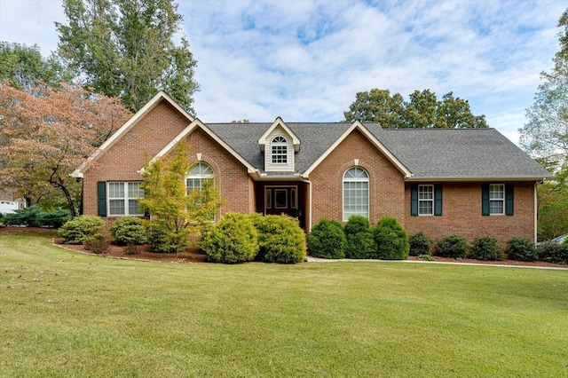 view of front of property with brick siding, a front lawn, and roof with shingles