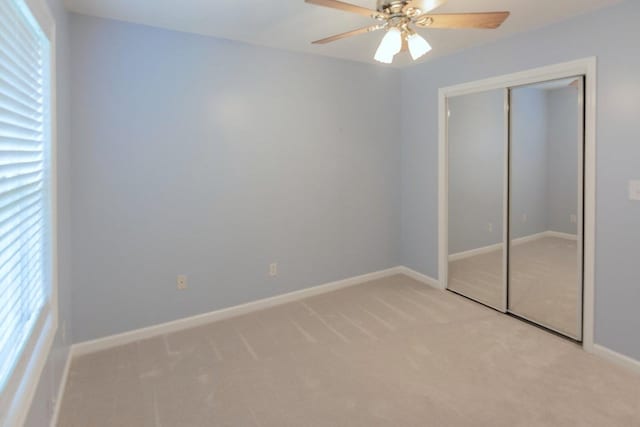 unfurnished bedroom with light carpet, a closet, a ceiling fan, and baseboards