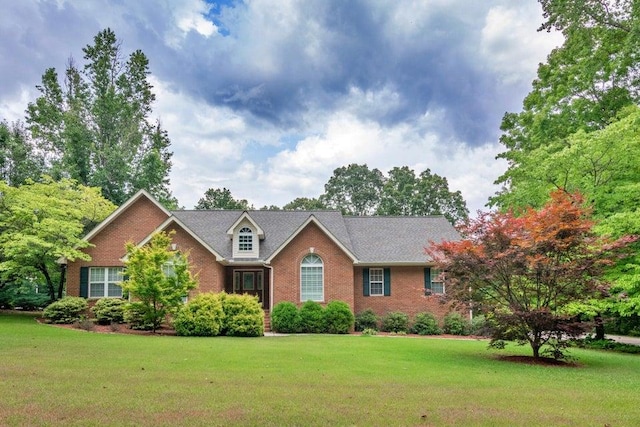 view of front facade with brick siding and a front yard