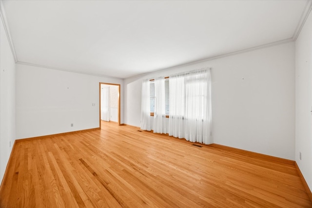 spare room featuring ornamental molding, light wood finished floors, visible vents, and baseboards