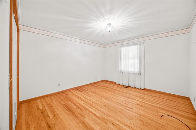 spare room featuring ornamental molding, wood finished floors, and baseboards