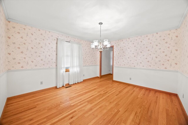 unfurnished room with light wood-style flooring, a wainscoted wall, visible vents, wallpapered walls, and crown molding