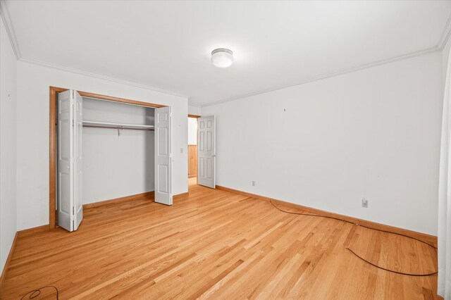 unfurnished bedroom with ornamental molding, a closet, wood finished floors, and baseboards