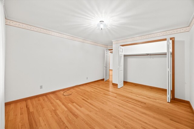 unfurnished bedroom with light wood finished floors, a closet, baseboards, and crown molding