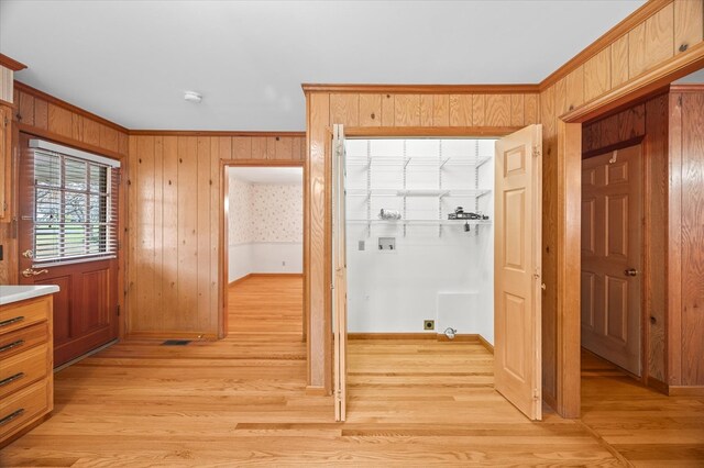 hall featuring wooden walls, visible vents, baseboards, light wood-type flooring, and crown molding