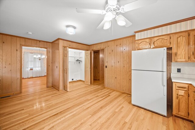 kitchen with light countertops, ornamental molding, light wood-type flooring, and freestanding refrigerator