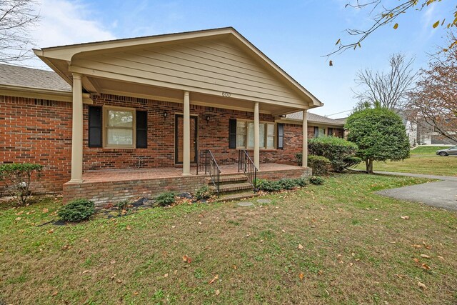 view of front of property with a front yard, a porch, and brick siding