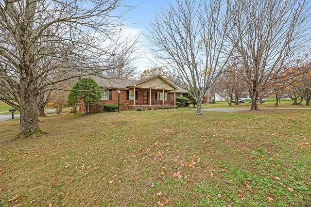 view of front of house with brick siding, a porch, and a front yard