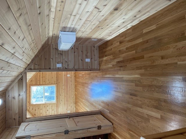 interior space featuring vaulted ceiling, wooden ceiling, wood walls, and wood finished floors