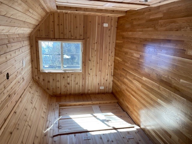 bonus room with wood ceiling, vaulted ceiling, and wooden walls