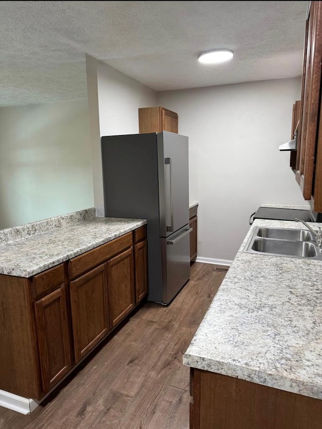 kitchen featuring a sink, a textured ceiling, dark wood-style floors, and freestanding refrigerator