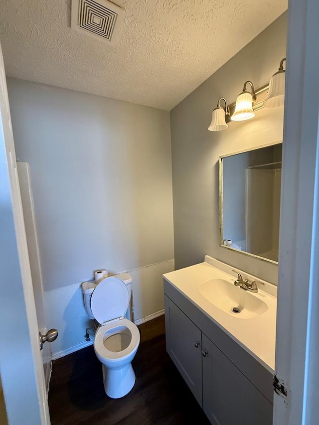 bathroom featuring vanity, wood finished floors, visible vents, a textured ceiling, and toilet