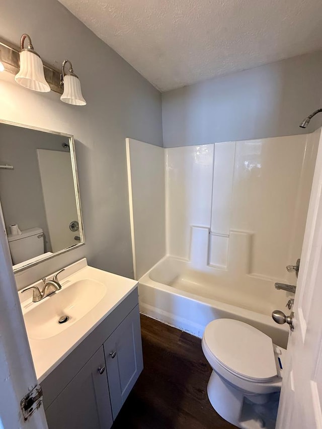 bathroom featuring a textured ceiling, toilet, shower / bath combination, and wood finished floors