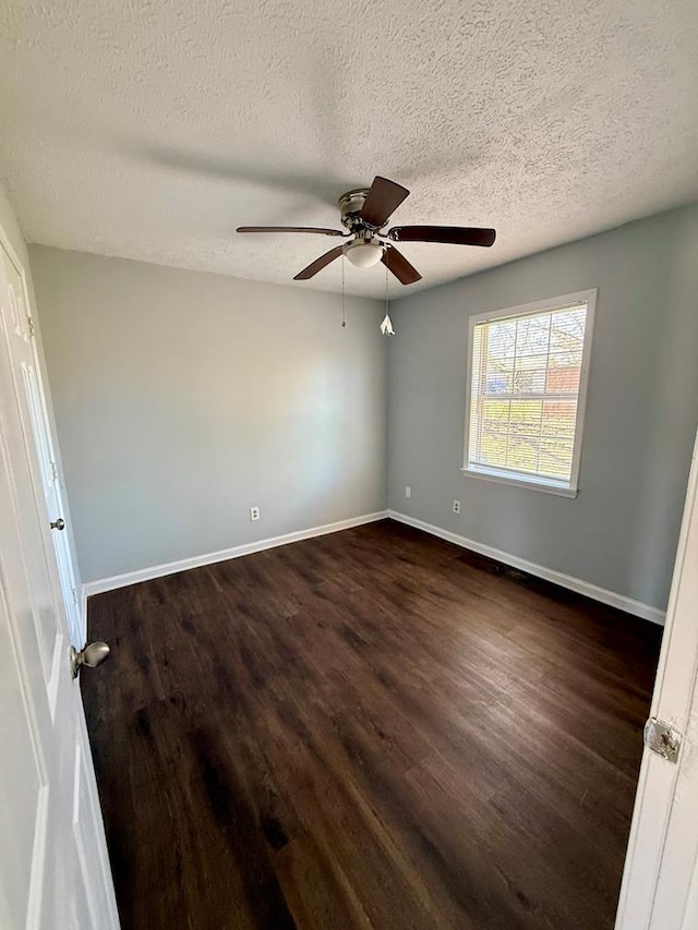 spare room featuring baseboards, dark wood-type flooring, and a textured ceiling