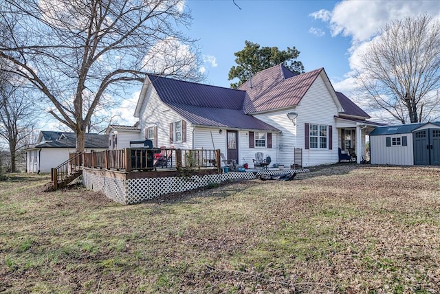 rear view of property featuring an outbuilding, a yard, metal roof, a deck, and a shed