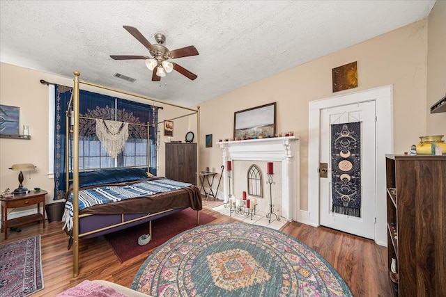 bedroom featuring a textured ceiling, wood finished floors, visible vents, and a ceiling fan