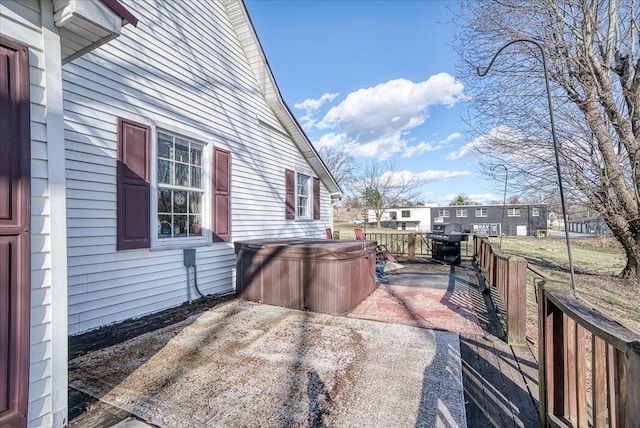 view of patio / terrace with a hot tub, fence, and a grill