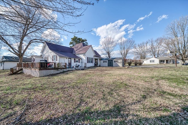 back of property featuring a deck, a yard, and an outbuilding