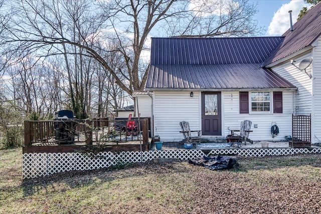 back of property with entry steps, metal roof, and a deck