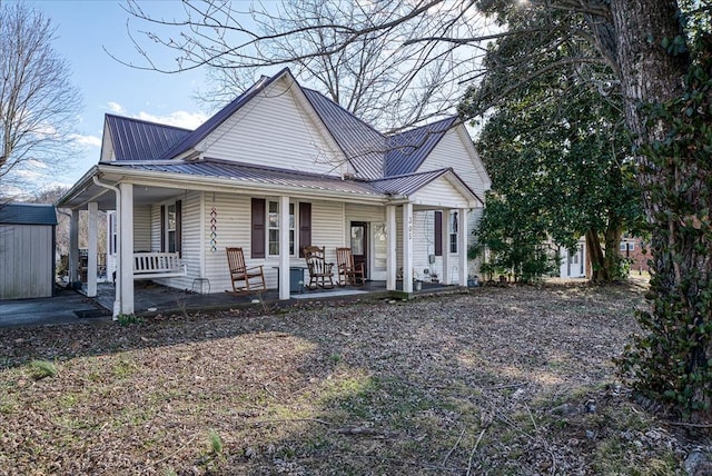 view of front of home with an outdoor structure, metal roof, a storage shed, and a porch