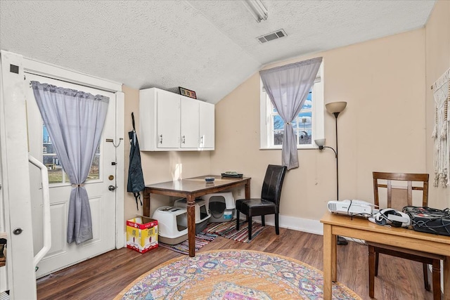 office area with baseboards, visible vents, wood finished floors, vaulted ceiling, and a textured ceiling