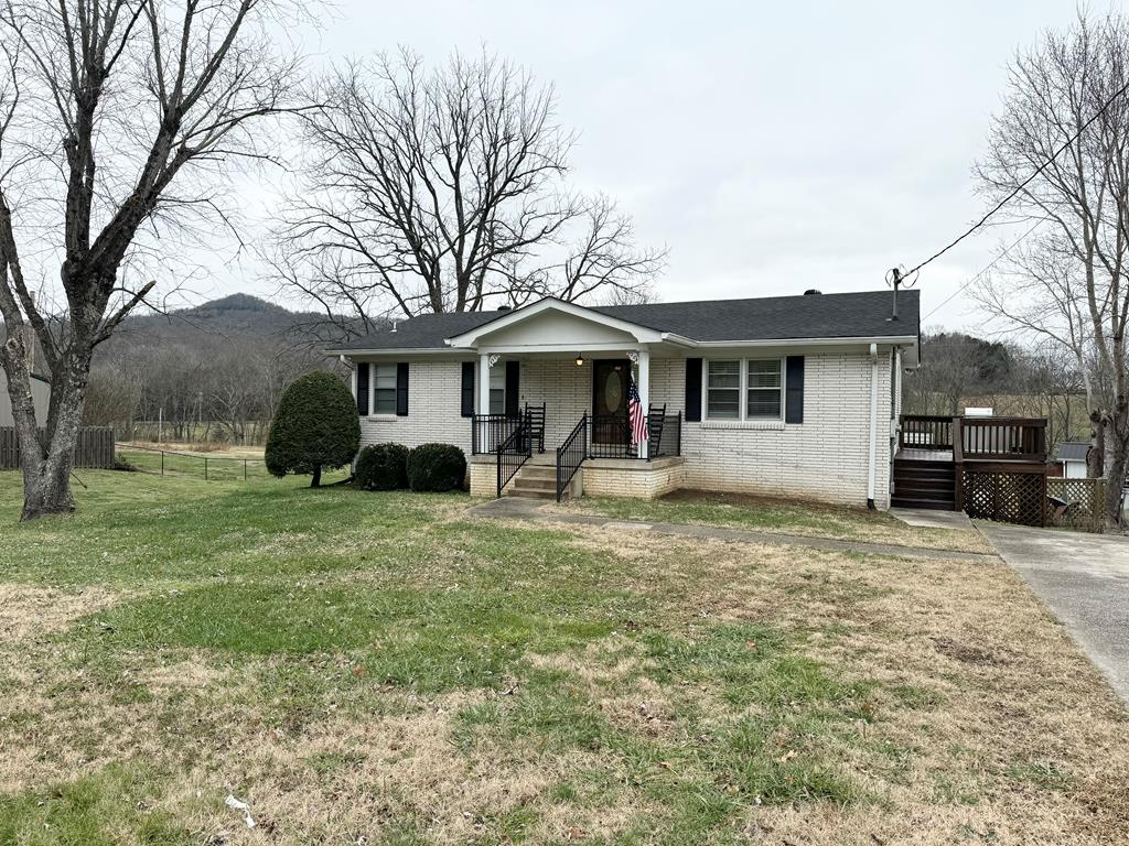 view of front of property featuring fence, a mountain view, a front lawn, and brick siding