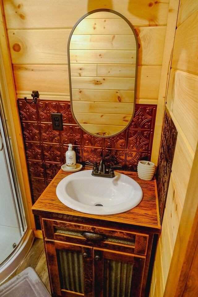 bathroom featuring wood walls, a shower stall, and vanity