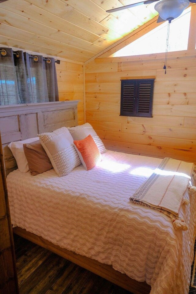 bedroom with lofted ceiling, wooden ceiling, visible vents, and wood walls