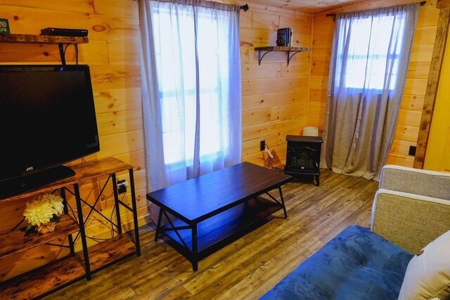 living room with a wood stove, wood walls, and wood finished floors