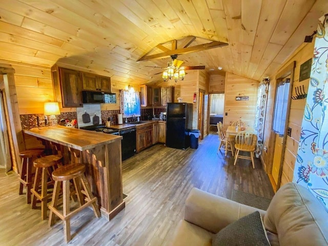 kitchen featuring wood ceiling, brown cabinets, wood finished floors, a peninsula, and black appliances