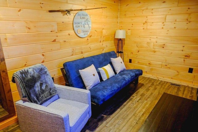 sitting room featuring wood finished floors, visible vents, and wooden walls