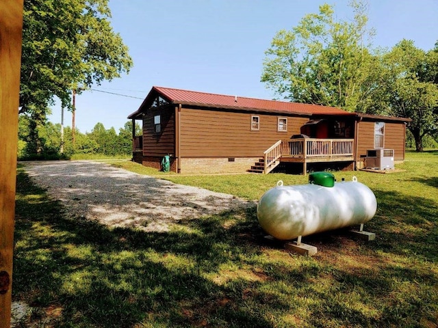 rear view of property with central AC unit, a lawn, metal roof, crawl space, and a wooden deck