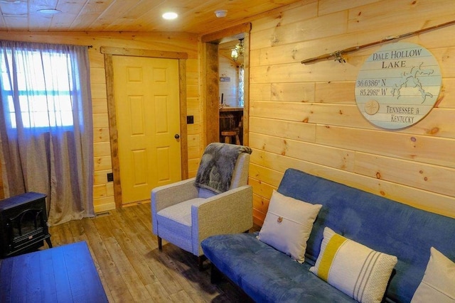 living room featuring wooden ceiling, wood finished floors, a wood stove, and wooden walls