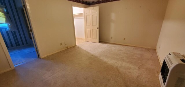 empty room featuring light carpet and heating unit