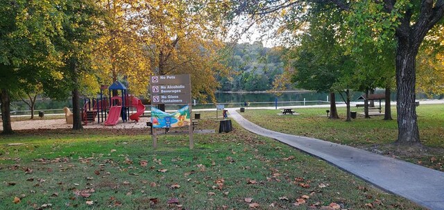 view of home's community featuring playground community, a yard, and a water view