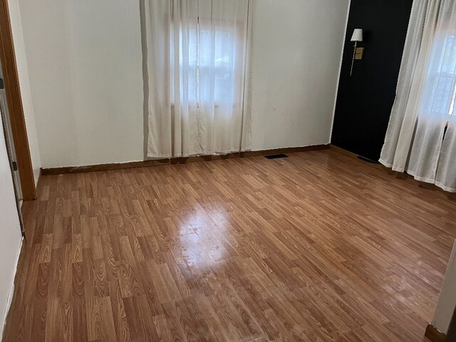 unfurnished bedroom with visible vents, baseboards, and wood finished floors